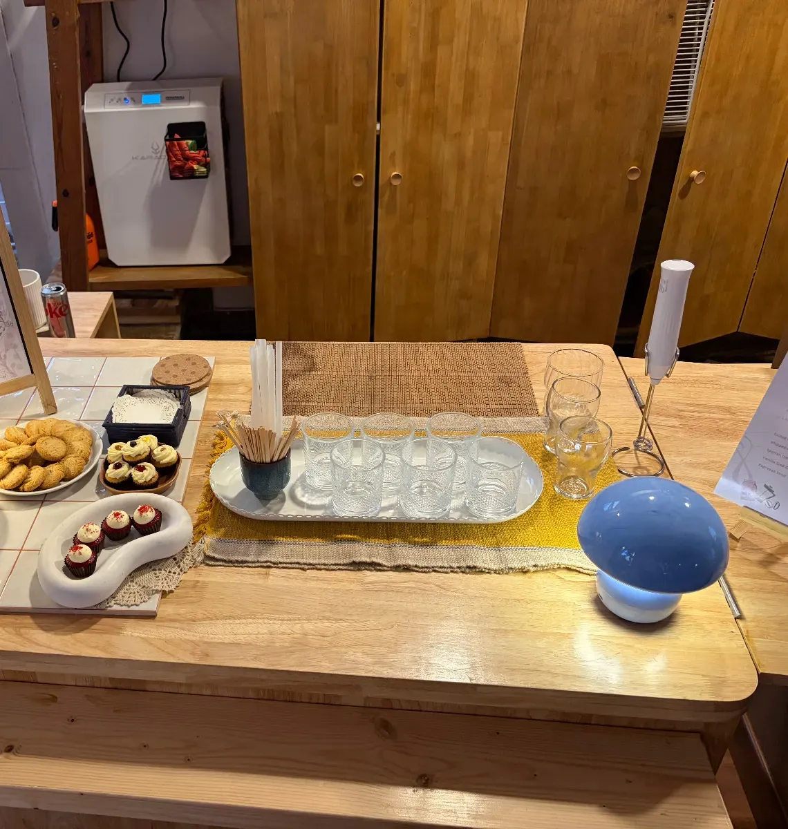 A spread of cookies, cupcakes and drinks laid out along the counter