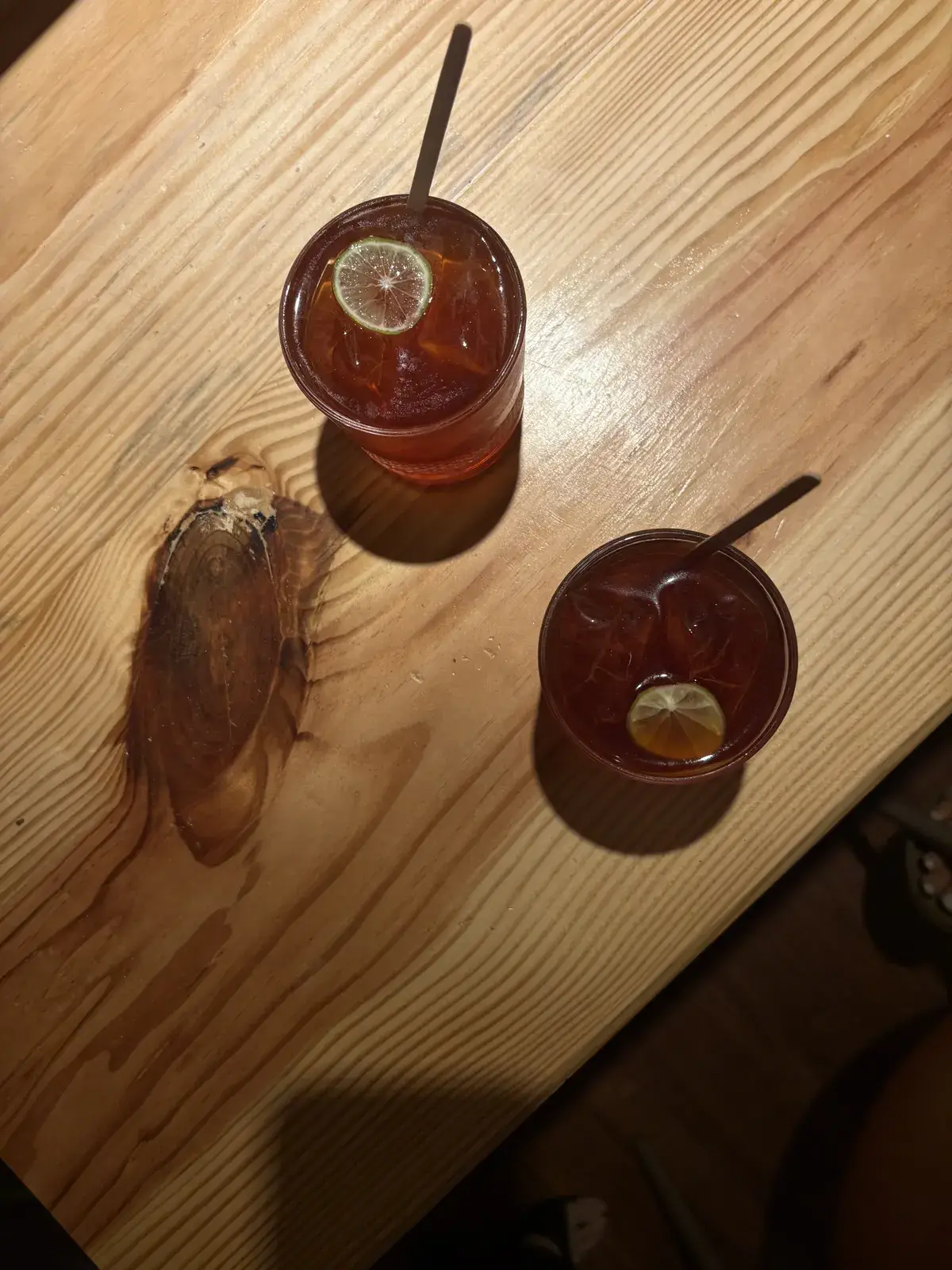 Two iced teas with lemon on the warm wooden counter, seen from above