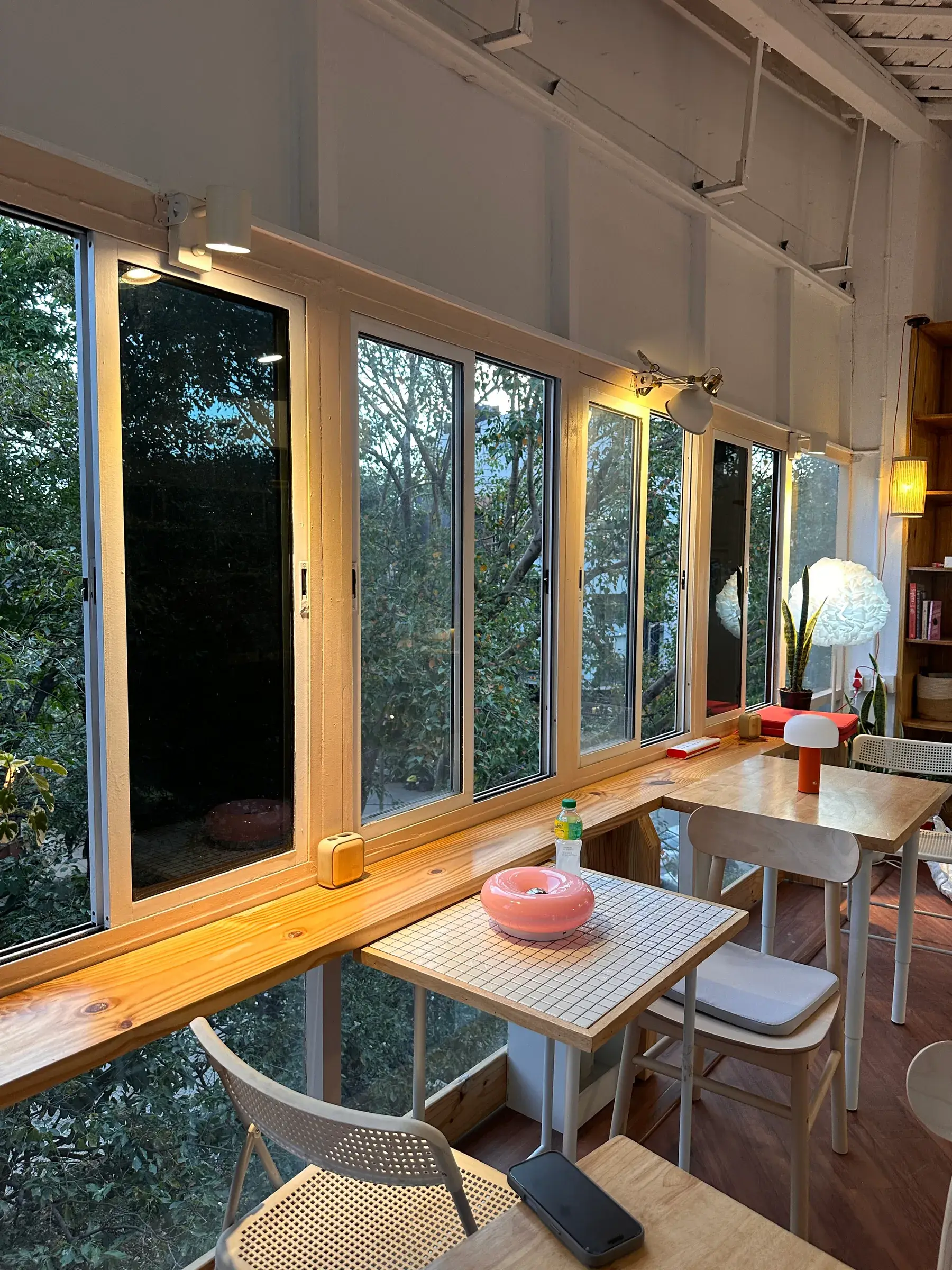 Corner table by the windows with a small glowing lamp and a pink candle