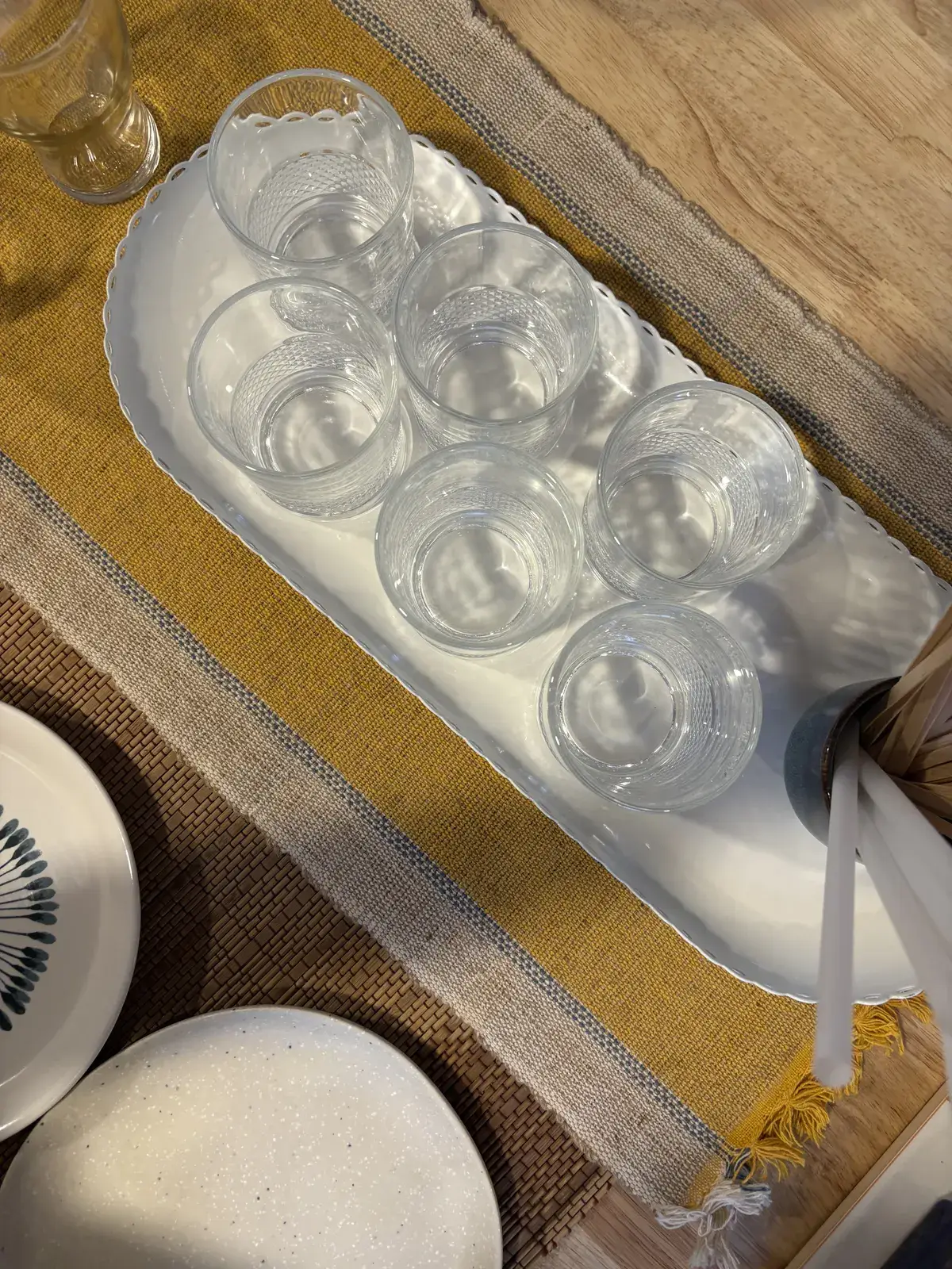 Looking down on a tray of cut-glass tumblers on a mustard table runner